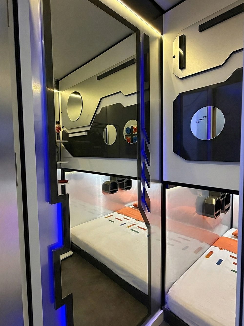 SleepPod Space interior with upper sleeping area, round window detail and blue LED lighting