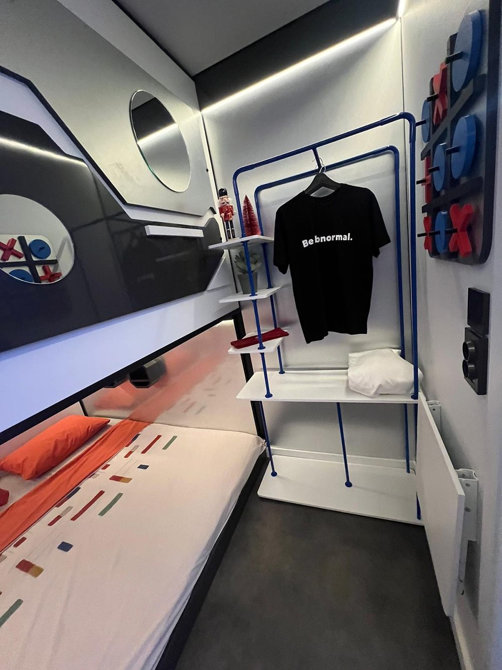 SleepPod Space sleeping space with blue clothes rail, shelves and wall graphics