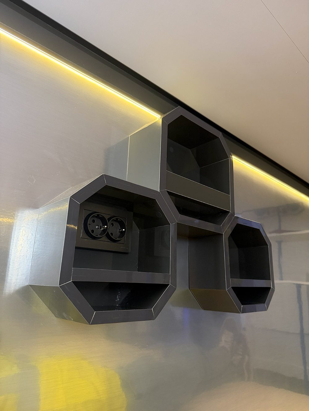 Hexagonal wall storage units with sockets under LED strip lighting in SleepPod Space