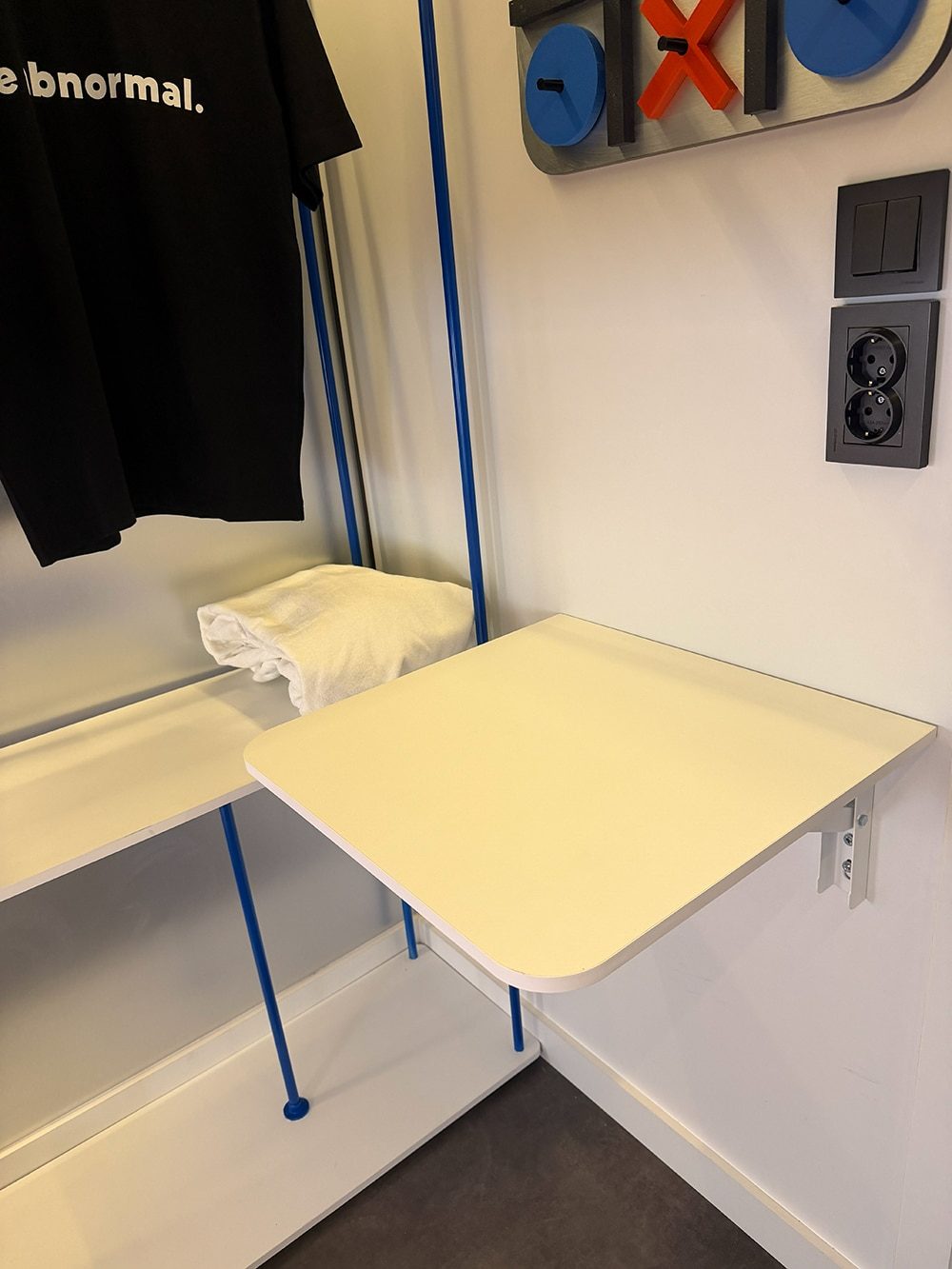 Foldable white work desk next to the clothes rail in a SleepPod Space capsule